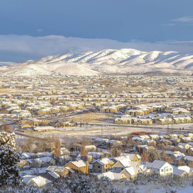 Kışın karlı vadi manzaralı evler ve donmuş dağlarla kaplı gökyüzüne karşı