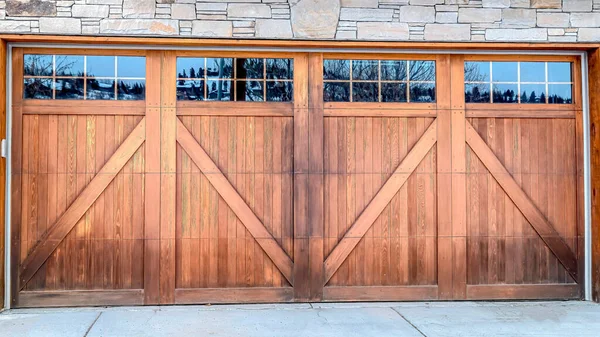 Pano Wide brown wood door with glass panes of attached garage of stone brick home — Foto de Stock