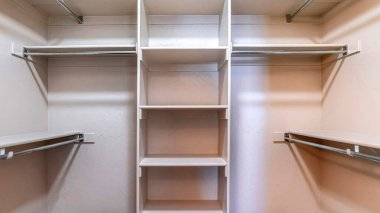 Pano, beyaz duvara karşı yapılmış kıyafetler için boş raflarla dolaba gir.