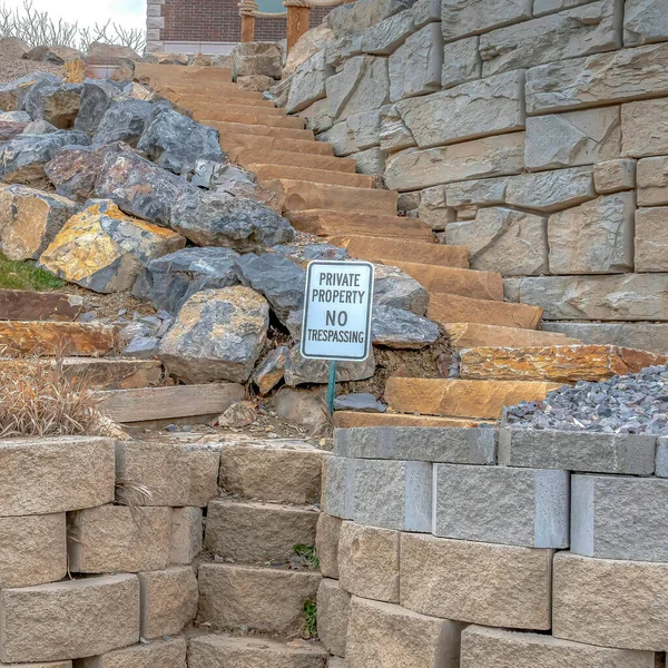 Square Stone retaining wall and steps with No Trespassing sign at a private property