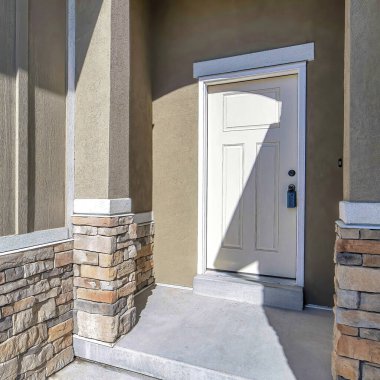 Güneşli bir günde, girişi kapı eşiği ve beyaz ön kapısı olan meydan girişi.