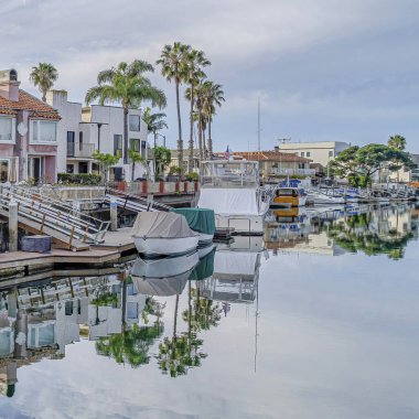 Kare Mavi gökyüzü ve bulutlar evlerle ve rıhtımlarla çevrili kanalların suyuna yansıyor