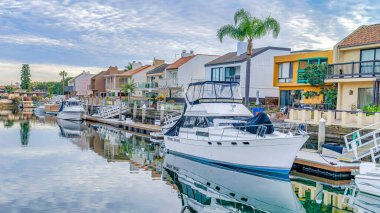 Pano, tekneleri ve özel rıhtımı olan manzaralı kanallara bakan evlerin üzerinden bulutlu gökyüzü.
