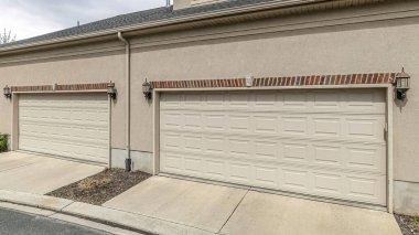 Evin garajının üstünde geniş beyaz garaj kapıları olan Gable Rood 'lu Pano Dormers.