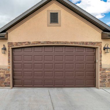 Bulutlara ve mavi gökyüzüne karşı eve bağlı iki araba garajının kare ön görüntüsü