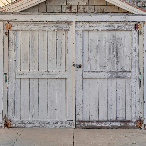 Poubelles carrées devant le vieux hangar avec toit en pente et porte en bois contre les maisons — Photo