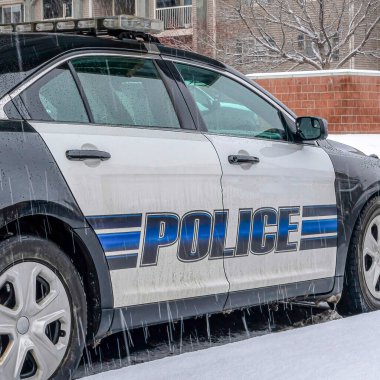 Karlı ve yağmurlu bir günde mahalleye park etmiş siyah beyaz polis arabası.