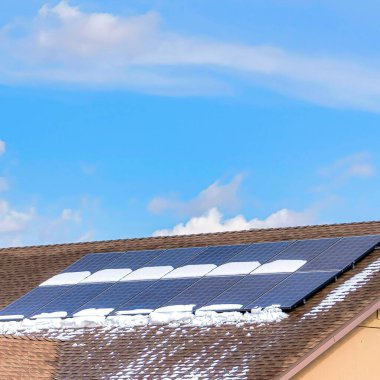 Kare, güneş panelleri yüklü bir evin karlı ve nemli çatısına odaklan