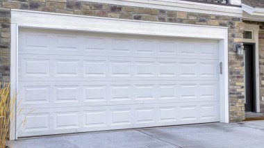 Evin ön kapısı. Balkonun altındaki beyaz garaj kapısı. Garaj yoluna bakıyor.