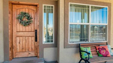 Pano House cephesi açık verandalı ve kahverengi ahşap kapılı, neşeli çelenkli.