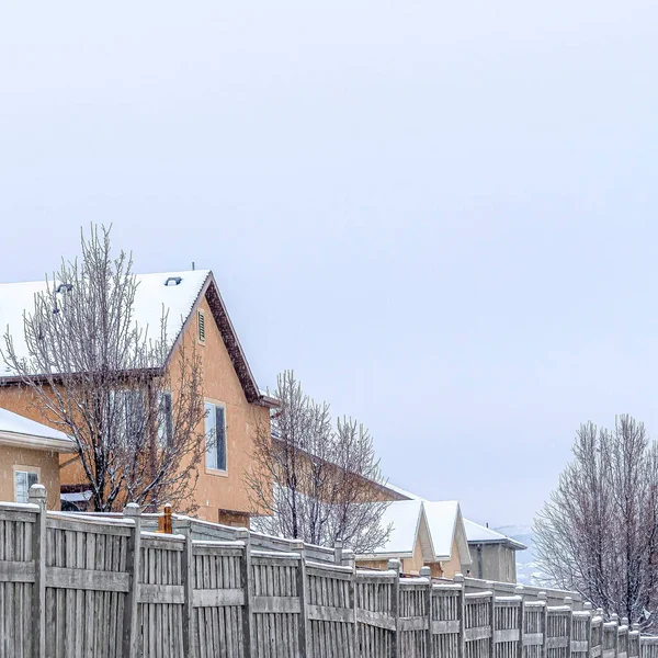 Lado quadrado da estrada nevado ao longo de cercas de madeira de casas em um belo bairro — Fotografia de Stock