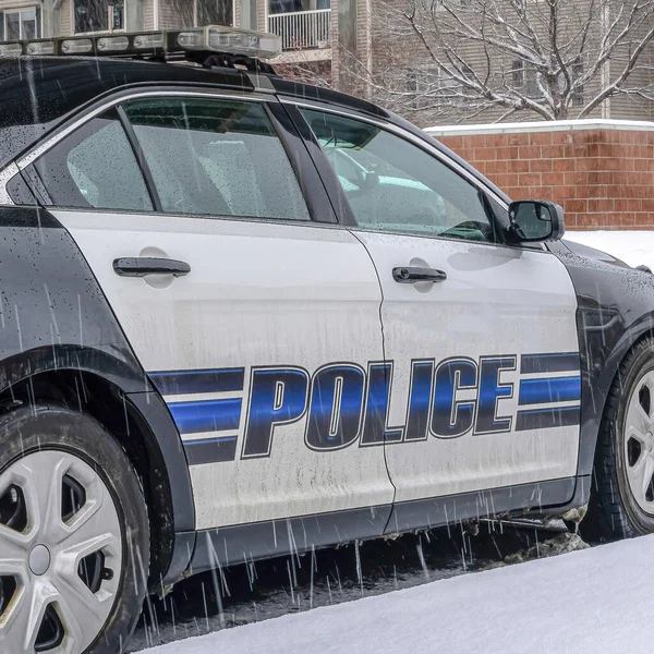 Square Black and white police car parked in the neighborhood on a snowy and rainy day — Stock Photo, Image