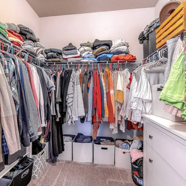 Ropa cuadrada dentro de un walk in closet de casa con alfombra en piso y pared blanca — Foto de Stock