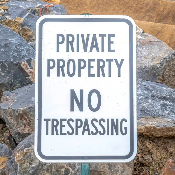 Square Private Property No Trespassing sign against jagged rocks and stone stairway — Stock Photo, Image