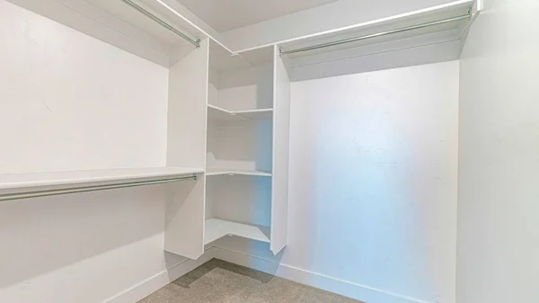 Pano Interior de un walk in closet con estantes y varilla de ropa montada en pared blanca — Foto de Stock