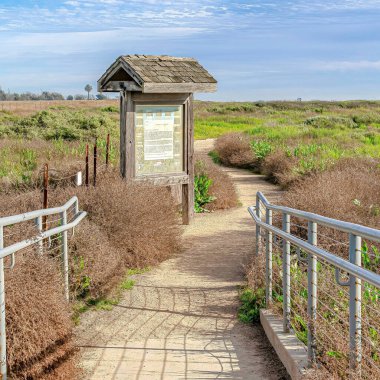 Huntington Plajı 'ndaki çimlerin üzerinde çatısı olan korkuluklu ve tabelalı Square Pathway.