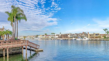 Huntington Sahili 'nde, bulutlu mavi gökyüzünün altında denizi çevreleyen Pano evleri ve rıhtımları