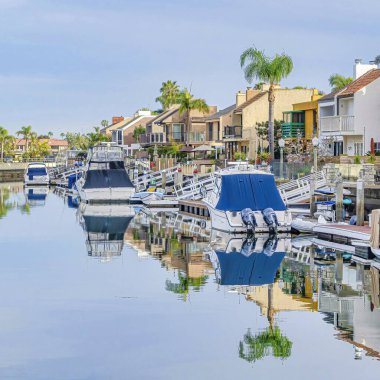 Açık denizde tekneleri olan ve bulutlu gökyüzünü yansıtan özel rıhtımı olan kare evler.