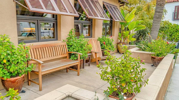 Pano Patio relajante de casa con silla de madera y banco contra ventanas con toldo —  Fotos de Stock