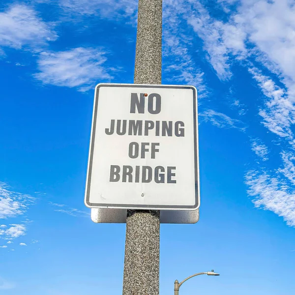 Square No Jumping Off Bridge znak na słupku lampy przed niebieskim niebem i chmury puchate — Zdjęcie stockowe