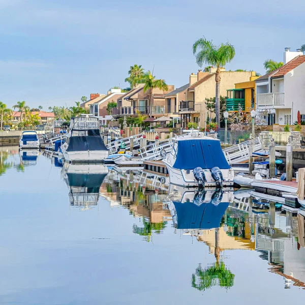 Vierkante huizen met prive-dokken op heldere zee met boten en reflecterende bewolkte skyscape — Stockfoto