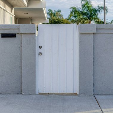 Kare beyaz kapı ve beton çit ağaçlar ve güzel evin bulutlu gökyüzü