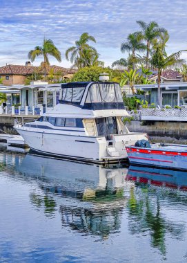 Dikey Yatlar ve tekneler deniz kenarındaki evlerin özel rıhtımlarında bulutlu mavi gökyüzünün altında