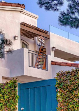 Dikey Mavi kapı ve çitlerle çevrili sarmaşıklar ile balkon ve beyaz dış duvar