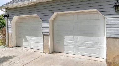 Pano dış görünüş, iki beyaz kapılı evin garajı.