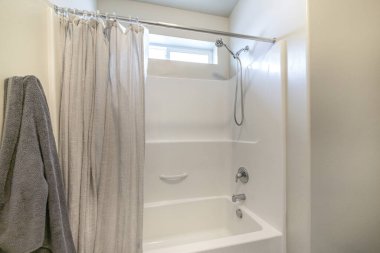 Banyo içi küvet duş ve pencere kombinasyonuyla dolu.