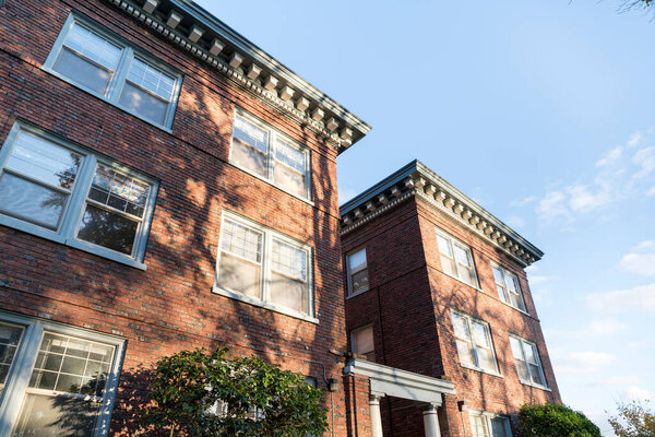 Two traditional buildings with bricks at Tacoma, Washington. Low angle view of two building exterior with bricks and windows with a shadow of trees under the sunlight.