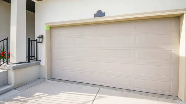 Pano Exterior de una casa con puerta de garaje cerrada y parte de una entrada de porche con escaleras — Foto de Stock