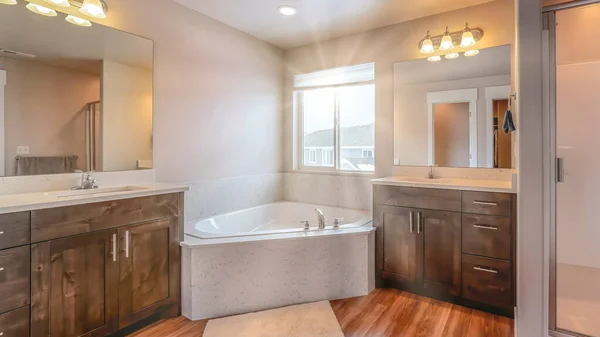 Красивая домашняя ванная комната со встроенной угловой ванной между двумя блоками тщеславия — стоковое фото