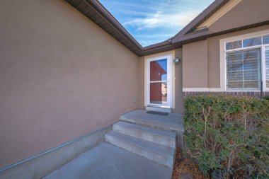 Merdivenleri ve çalıları olan bir evin beton kapısı.