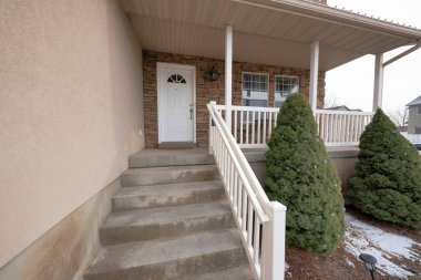 Merdivenleri ve süs ışıkları olan küçük çam ağaçları olan bir evin dışında.