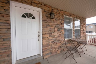 Ön kapıda taş tuğlalar, sandalyeler ve masa var.