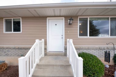 Vinil ahşap ve tuğla kaplamalı bir evin ön kapısı.