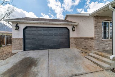 Kapalı köşe siyah garaj kapısı dış tarafı beton bir garaj yolu.