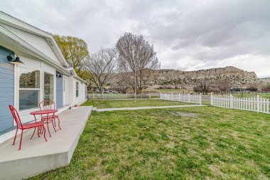 Beton güverteli ve beyaz ahşap çitli bir evin ön bahçesi.