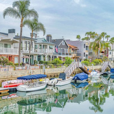 Kare botlar Long Beach 'teki deniz kenarındaki evler boyunca bir kanalın duvarına kenetlenmiş.