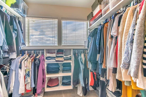 Walk in closet interior con ropa colgante y una vista de un cielo nublado a través de las ventanas — Foto de Stock