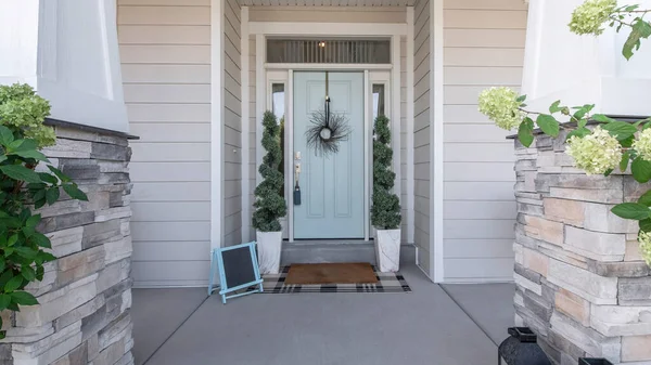 Pano Entrée d'une maison avec porte d'entrée décorative bleu clair et poteaux avec briques de pierre — Photo