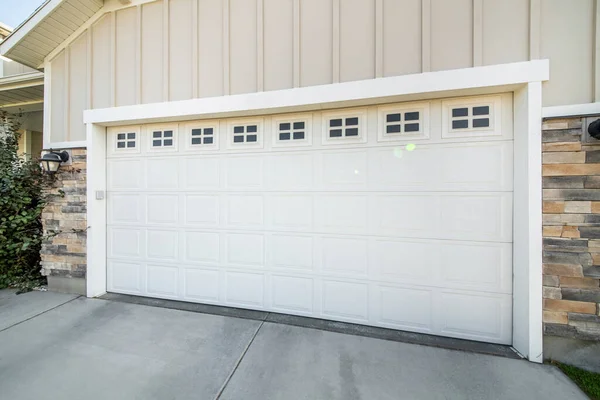 Garaje exterior con entrada de hormigón y puerta seccional blanca con paneles de ventanas — Foto de Stock