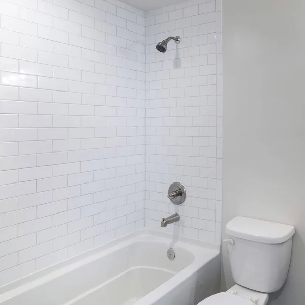 Square frame Interior of a bathroom with vanity sink and shower tub combo with subway tiles wall surround