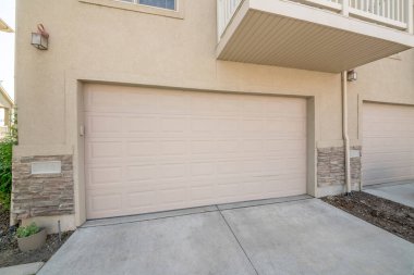 Balkonlu bir kasaba evinin bej bölümlü garaj kapıları