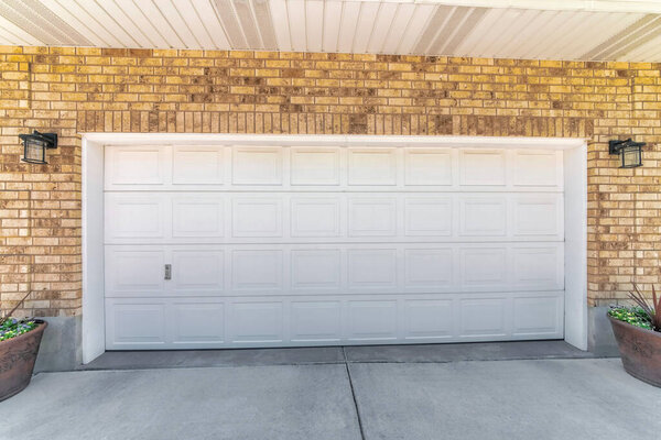 Внешний вид гаража с белой секционной дверью и коричневым кирпичом сайдинг