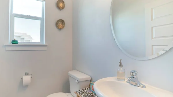 Pano Interior de um banheiro branco com janelas, espelho, pia e armário — Fotografia de Stock