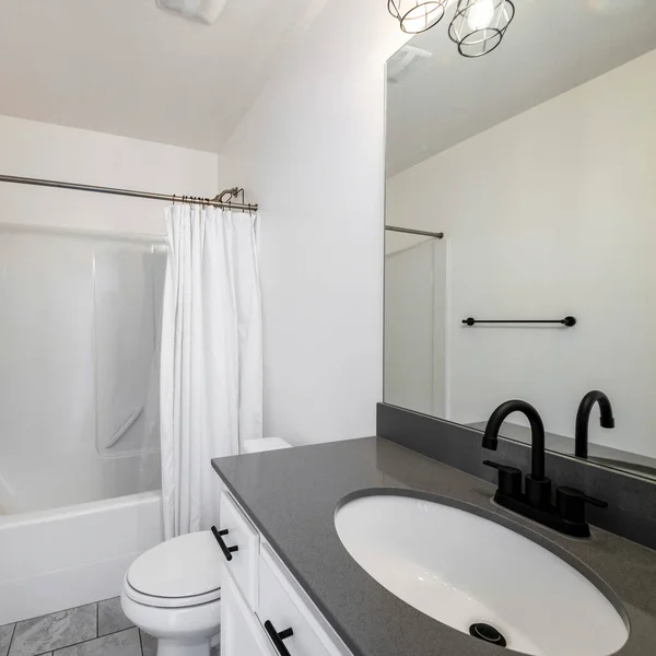 Интерьер ванной комнаты с черными светильниками и одна часть ванной с душем с белой занавеской — стоковое фото