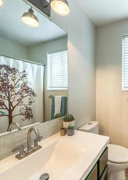 Маленькая ванная комната с окном и тщеславием с белой столешницей и встроенной раковиной — стоковое фото