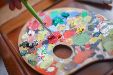 Boya tahtasında kırmızı boya karıştırmak.